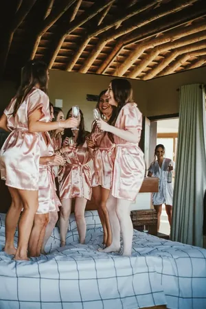 Wedding photo: bridesmaids pink robes dancing bed