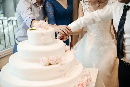 Wedding photo: couple cutting white cake pink roses