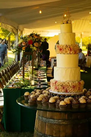 Wedding photo: tall tiered cake cupcakes barrel outdoor